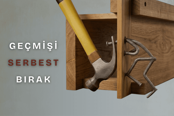 Ahşap bloğa çakılı bir çividen yapılmış kaçmaya çalışan insan figürü, çiviyi sökmeye çalışan sarı saplı bir çekiç ve sol tarafta "GEÇMİŞİ SERBEST BIRAK" yazısı.